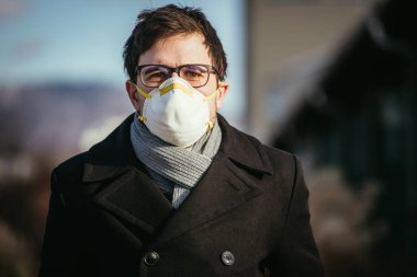 Dışarıda solunum maskeli genç bir adam. Flue ve corona mevsimi