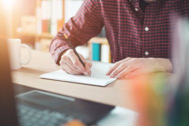 Beyaz bir çarşafa yazı yazan genç bir adam.