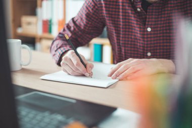 Beyaz bir çarşafa yazı yazan genç bir adam.