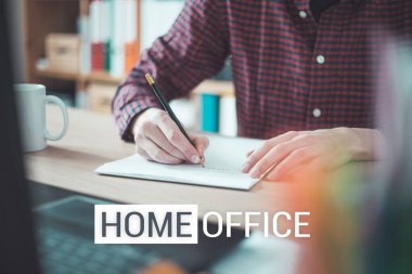 Beyaz bir çarşafa yazı yazan genç adam, ev ofisinin içinde, 