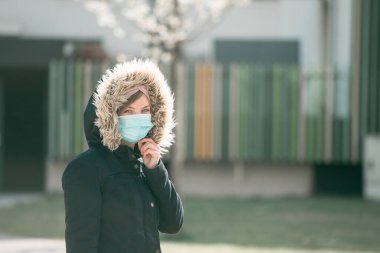 Dışarıdaki genç kadın maske takıyor. Corona virüsü ve grip mevsimi.