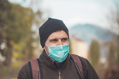 Dışarıda maske takan genç bir adam. Corona virüsü ve grip mevsimi.