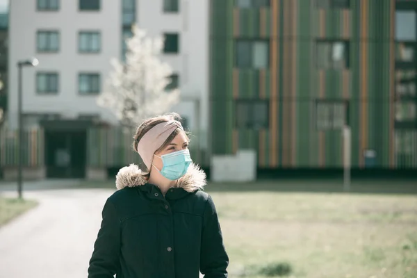 Young woman outdoors putting on face mask. Corona virus and flu season.