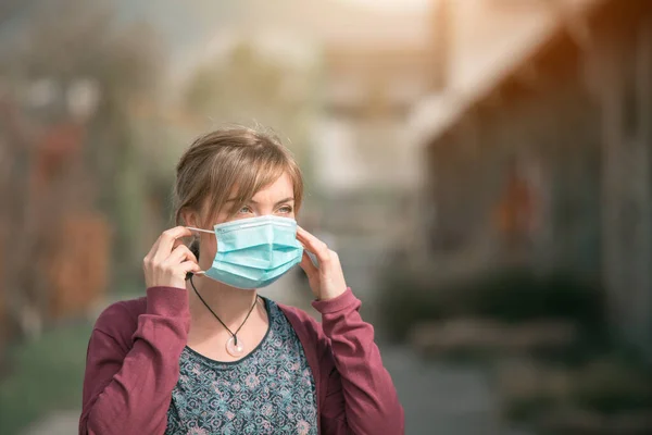 若い女性の屋外の顔のマスクを置く コロナウイルスとインフルエンザの季節 — ストック写真