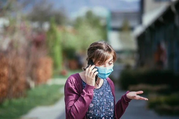 屋外でフェイスマスクとスマートフォンを身に着けている若い女性 コロナウイルスとインフルエンザの季節 — ストック写真