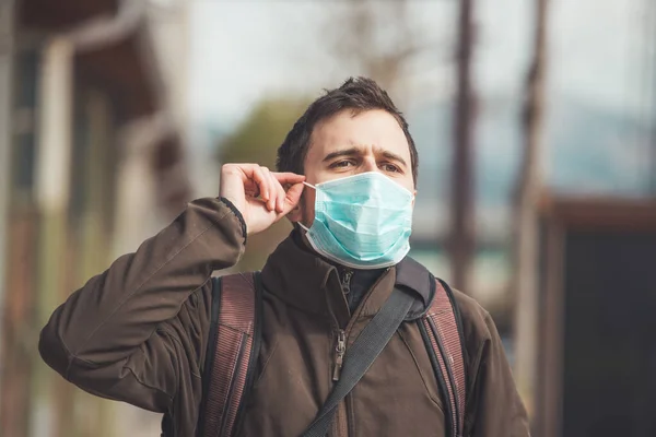 若い男は屋外の顔のマスクを置く コロナウイルスとインフルエンザの季節 — ストック写真