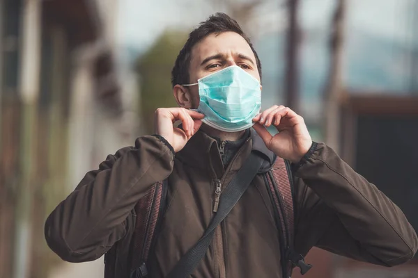 Young man outdoors putting on face mask. Corona virus  and flu season.