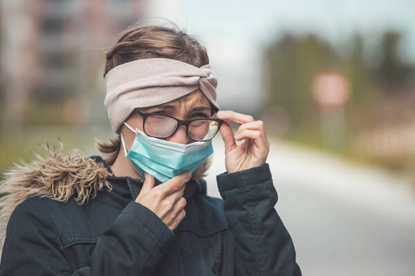 Young woman outdoors wearing a face mask and glasses, tarnished glasses 