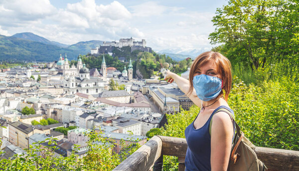 Female tourist with face mask is enjoying the view over the historic district of Salzburg