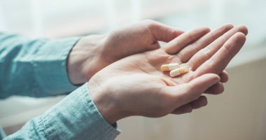 Erkek eli uyuşturucu ya da vitamin hapı tutuyor