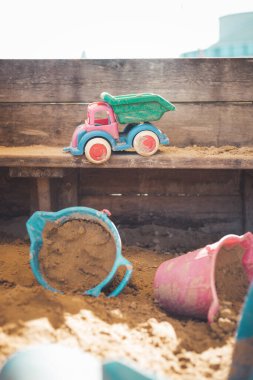 Children plastic toys in the sand box. Dirt bucket, selective focus.  clipart