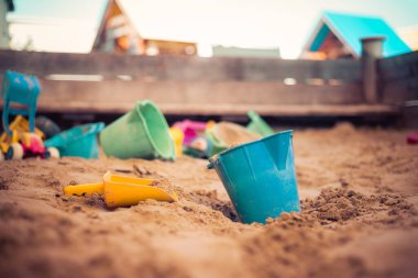 Çocuklar kum havuzunda plastik oyuncaklar. Pislik kovası, seçici odaklanma. 