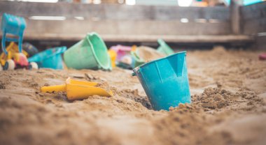 Çocuklar kum havuzunda plastik oyuncaklar. Pislik kovası, seçici odaklanma. 