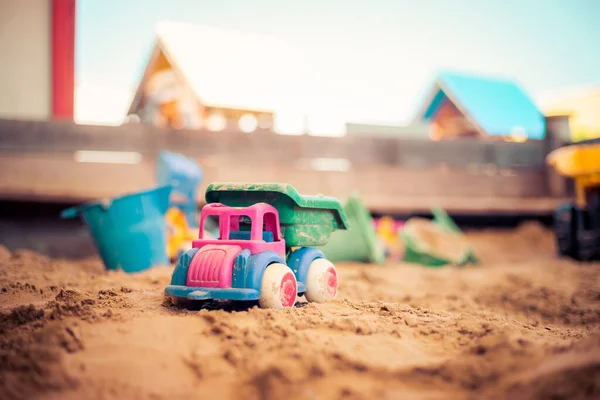 Children plastic toys in the sand box. Truck, selective focus.