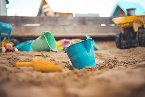 Children plastic toys in the sand box. Dirt bucket, selective focus.