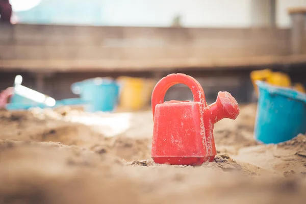 Children plastic toys in the sand box. Watering can, selective focus.