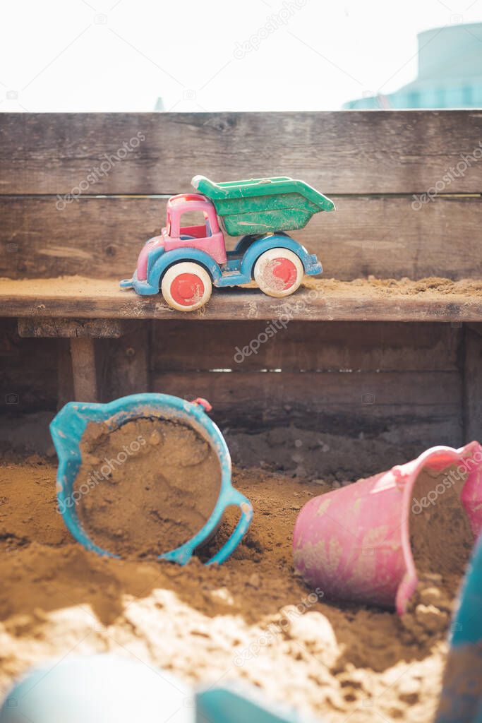 Children plastic toys in the sand box. Dirt bucket, selective focus. 