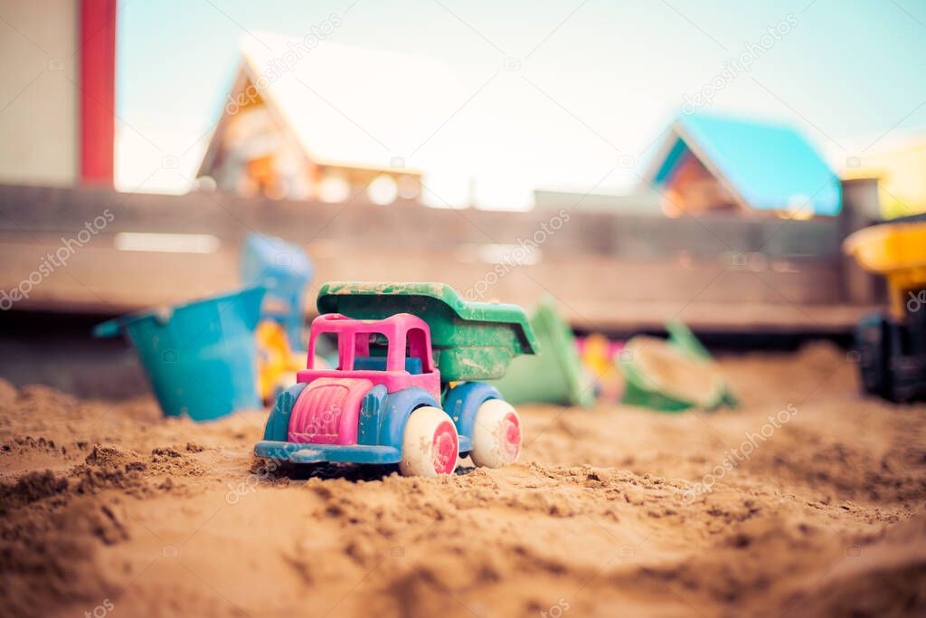Children plastic toys in the sand box. Truck, selective focus. 