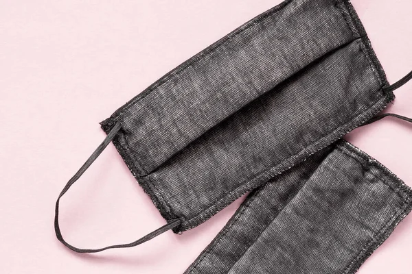 Pembe arka planda koruyucu pamuk maskeler. Siyah kumaş gazlı bez maskesi. Coronavirus enfeksiyon koruması