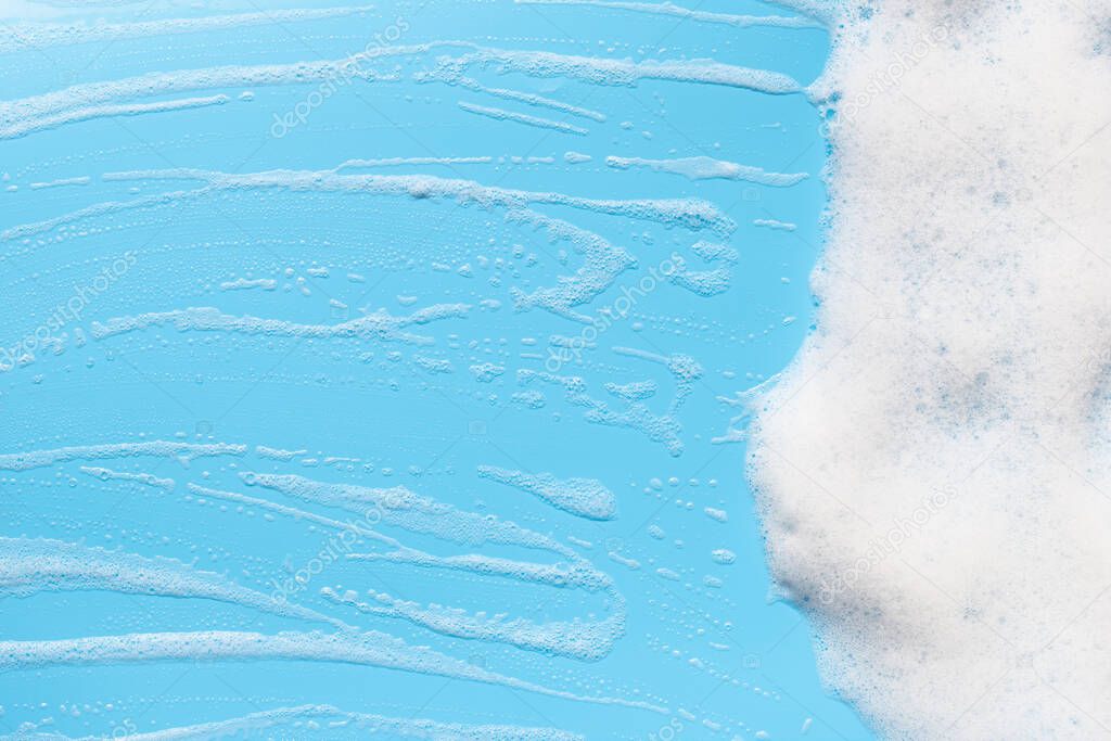 Foam on blue background. Shampoo, soap, shower gel soapy bubbles.  Bath hygiene frame. Abstract cleansing foam texture