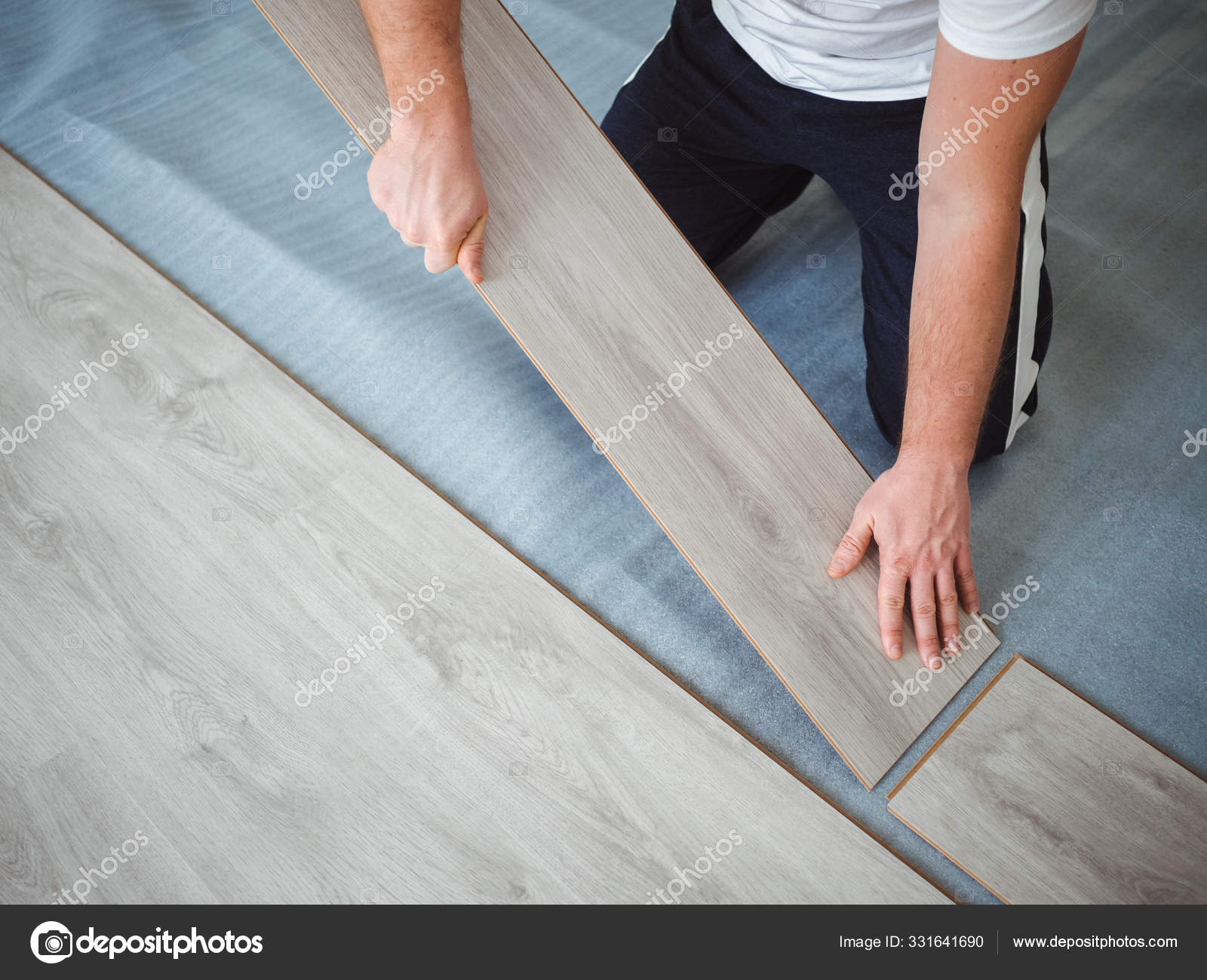 A man is laying laminate flooring. The repair process in the room