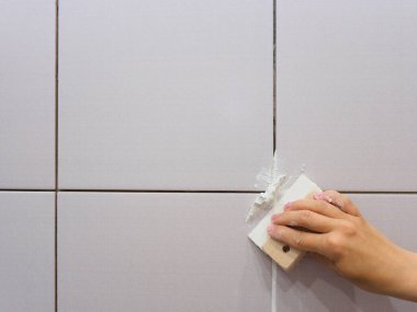 Banyodaki fayanslar arasında sayıyorum. Kadın eli bir spatula tutuyor. Onarım.