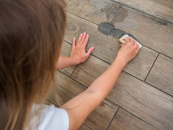 Grouting between ceramic tiles. The girl works with a spatula. Repair in the room.