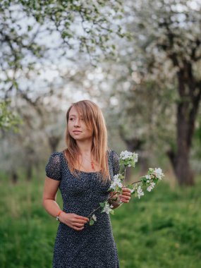 Bahar yeşili bir bahçede mavi elbiseli genç bir kızın portresi..