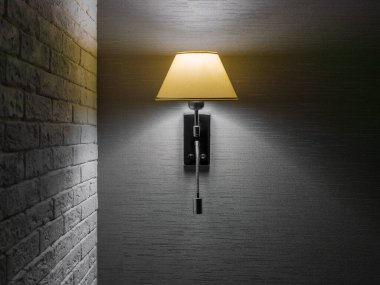 Abajur altında, duvara asılı, tuğla duvarın yanında gri duvar kâğıdı olan klasik bir şamdan. Boşluğu kopyala