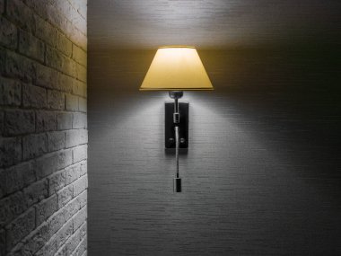 Classic sconce with turned on bulb under lampshade hanging on wall with gray wallpaper next to brick wall. Copy space clipart
