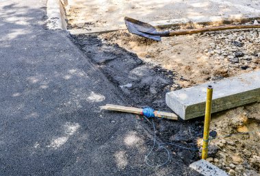 Yaya yolu yeni asfaltla kaplı. Kürek, ip seviyesi ve kaldırım taşı hemen yanında. Yolların onarımı