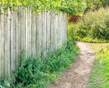Eski ahşap çit boyunca toprak patika. Kırsal alan. Yaz güneşli bir gün