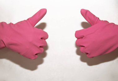 Beyaz bir arka planda iki ele giydirilmiş pembe eldivenler süper işaretler gösteriyor.
