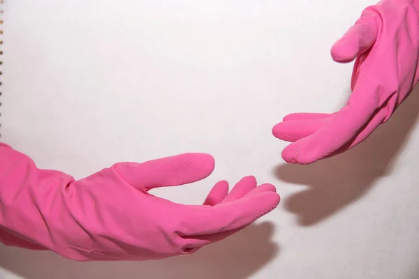 Pink household gloves dressed on both hands on a white background stretch to each other from two sides