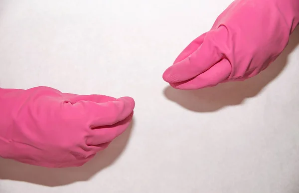 Pink medical gloves dressed on both hands on a white background in fists
