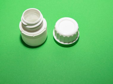 Üçüncü adım. Yeşil arka planda kapağı olan beyaz bir hap kavanozu açık.