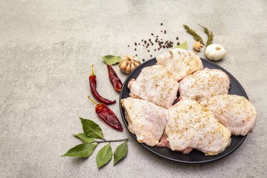 Çiğ tavuk budu ve baharat. Taş zeminde et pişirmek için gerekli malzemeler. Acı ve karabiber, sarımsak, biberiye, defne yaprağı..