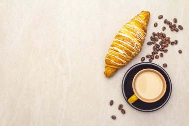 Kruvasanla birlikte bir fincan taze kahve. Taş zemin üzerindeki kavram, üst görünüm, kopyalama alanı.