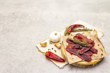Basturma, kurutulmuş sığır filetosu, kurutulmuş et, ince dilimlenmiş. Kuru biberiye, biber karışımı, kırmızı biber, kaliteli keten kumaşlı sarımsak. Tahtadaki lezzetli yemekler, taş zemin, kopyalama alanı..