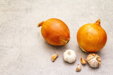 Taştan bir arka planda sarımsaklı dev soğan soğanları. Yemek pişirme arka planı, kopyalama alanı.