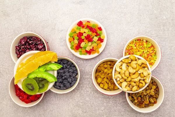 Gedroogde en gekonfijte vruchten en cashewnoten. Gesorteerd in keramische kommen op een stenen ondergrond. Gezond vegetarisch (veganistisch) voedingsconcept, kopieerruimte, bovenaanzicht. — Stockfoto