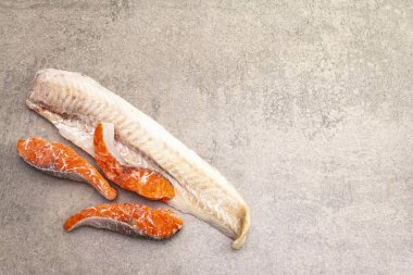 Çeşitli donmuş balıklar. Hake fileto ve somon parçaları. Sağlıklı yemek pişirmek için gerekli malzemeler. Taş aşçılık arka planı, kopyalama alanı.