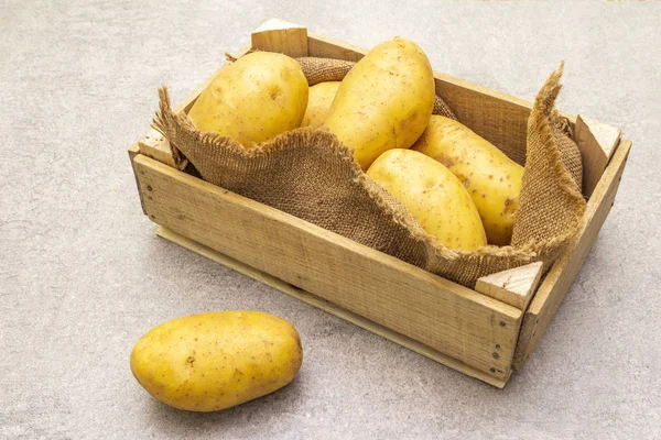 Сира нечиста молода картопля в дерев'яній ящиці. Новий урожай, на вереску, кам'яний фон, крупним планом . — стокове фото