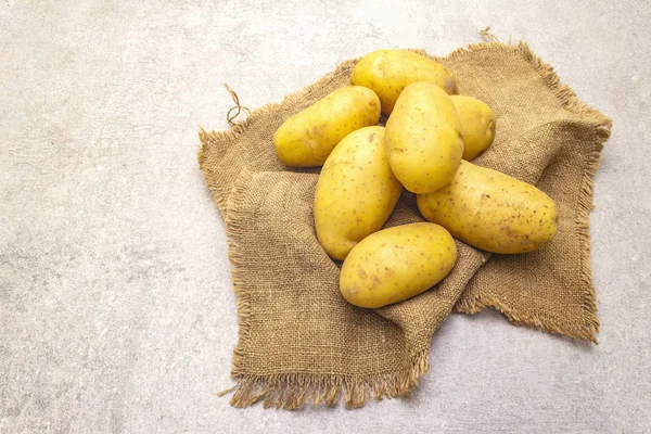 Raw unpeeled young potatoes on sackcloth. New harvest, heap on a stone background, close up. — 스톡 사진