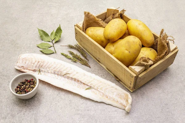 Petites pommes de terre crues et filets de merlu congelés. Ingrédients pour fish and chips. Épices et herbes sur fond de pierre, gros plan . — Photo