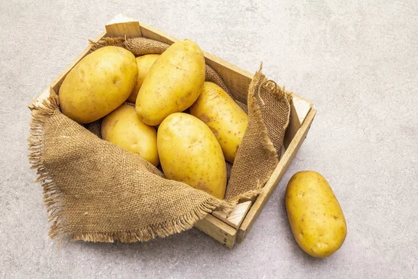Сира нечиста молода картопля в дерев'яній ящиці. Новий урожай, на вереску, кам'яний фон, вид зверху . — стокове фото