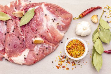 Çiğ domuz omuzu ve baharat. Saha yaprağı, sarımsak. Taştan bir arkaplanda, üst görünümü kapat..