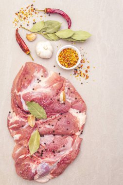 Çiğ domuz omuzu ve baharat. Saha yaprağı, sarımsak. Taştan bir arkaplanda, üst görünümü kapat..