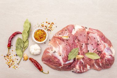 Çiğ domuz omuzu ve baharat. Saha yaprağı, sarımsak. Taştan bir arkaplanda, üst görünümü kapat..
