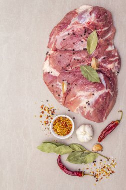 Çiğ domuz omuzu ve baharat. Saha yaprağı, sarımsak. Taştan bir arkaplanda, üst görünümü kapat..